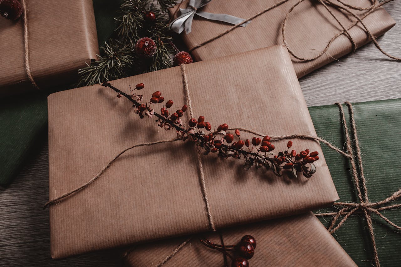 why-choose-us-01 Rustic brown paper Christmas gifts with twine and red berry accents on wooden background.